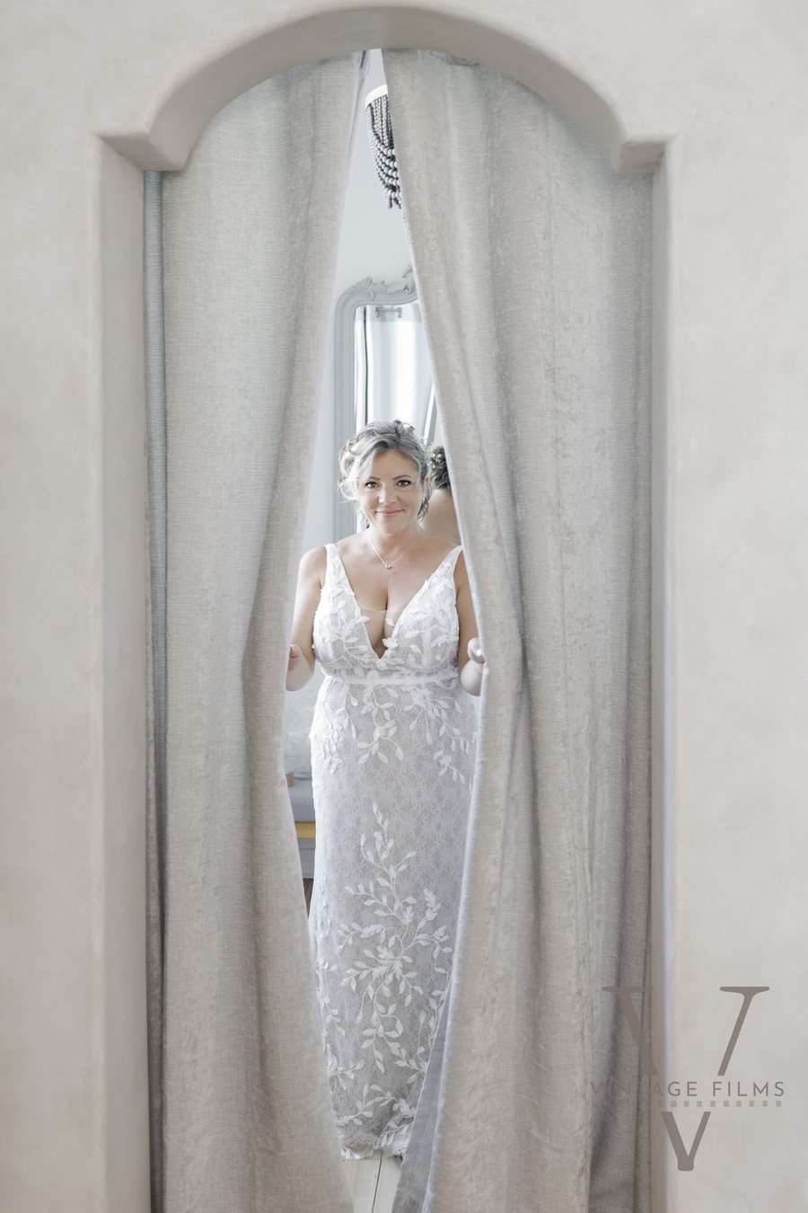 A bride parting the curtains of the arch